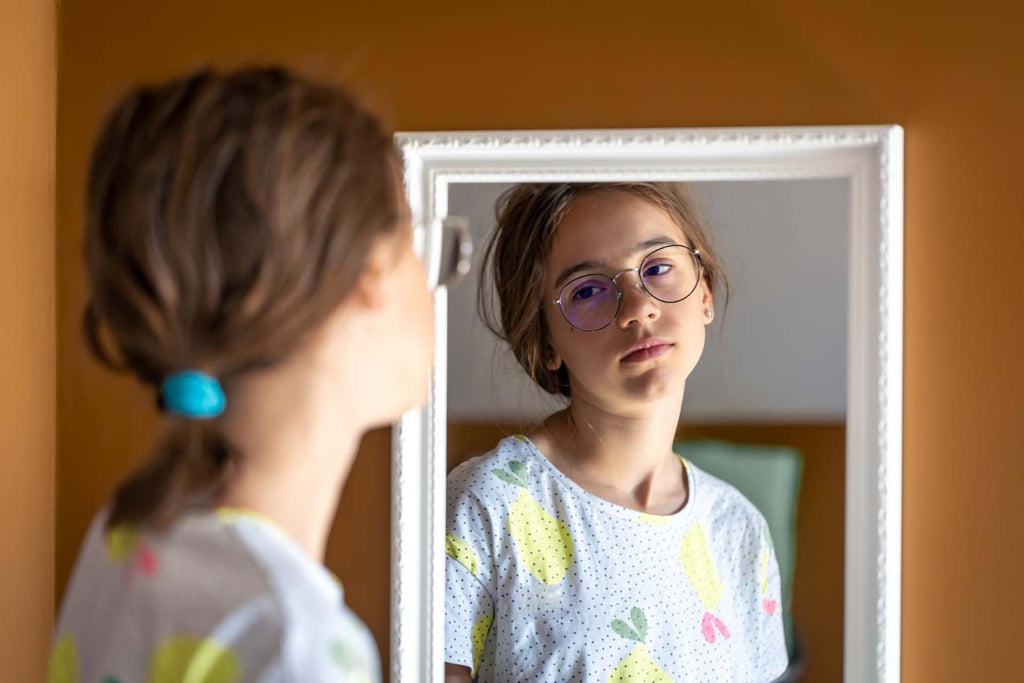 a teen gir looking at the mirror stressed and with low self-esteem