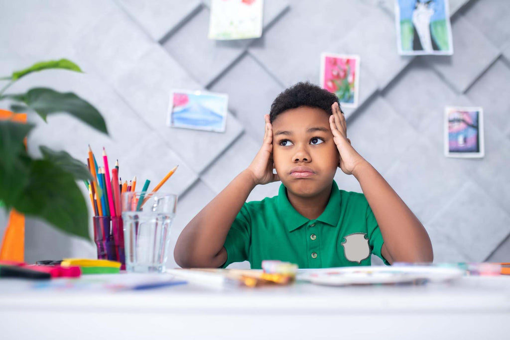boy of primary school age touching head with hands