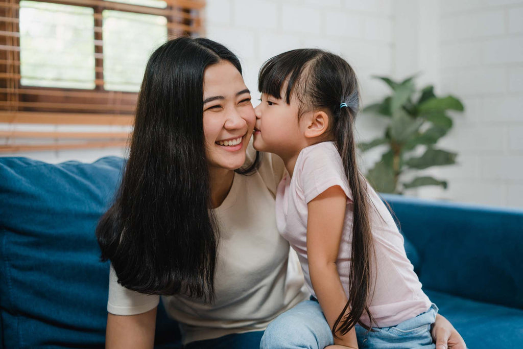 mom and daughter embracing kissing on cheek