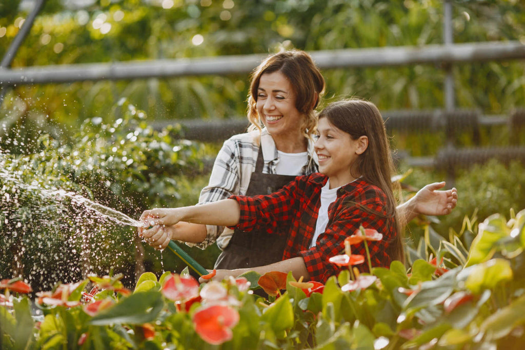 mother with daughter watering plants in the garden